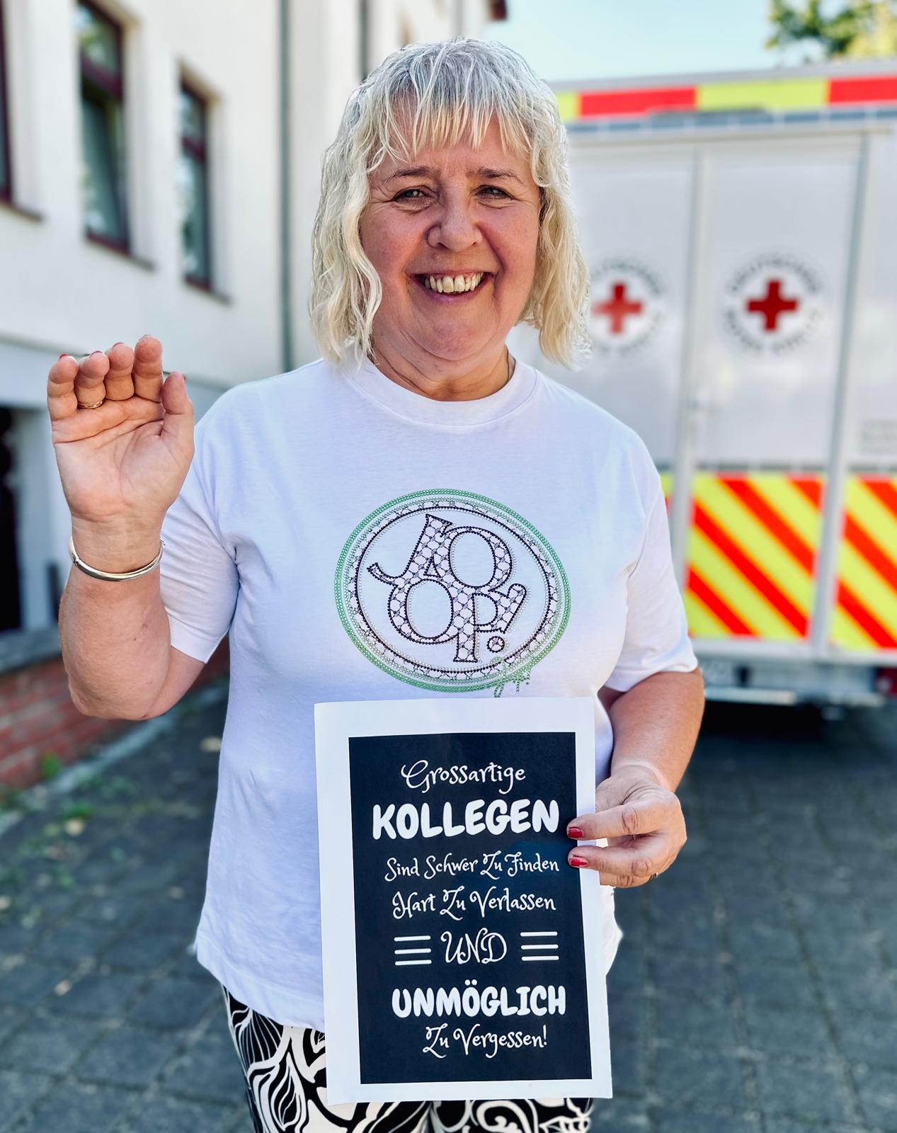 Lächelnde Person hält Schild mit Text: „Großartige Kollegen sind schwer zu finden, hart zu verlassen und unmöglich zu verg...