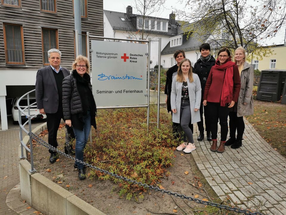 Gruppe von Menschen steht vor einem Schild mit der Aufschrift "Bildungszentrum Teterow gGmbH, Seminar- und Ferienhaus".