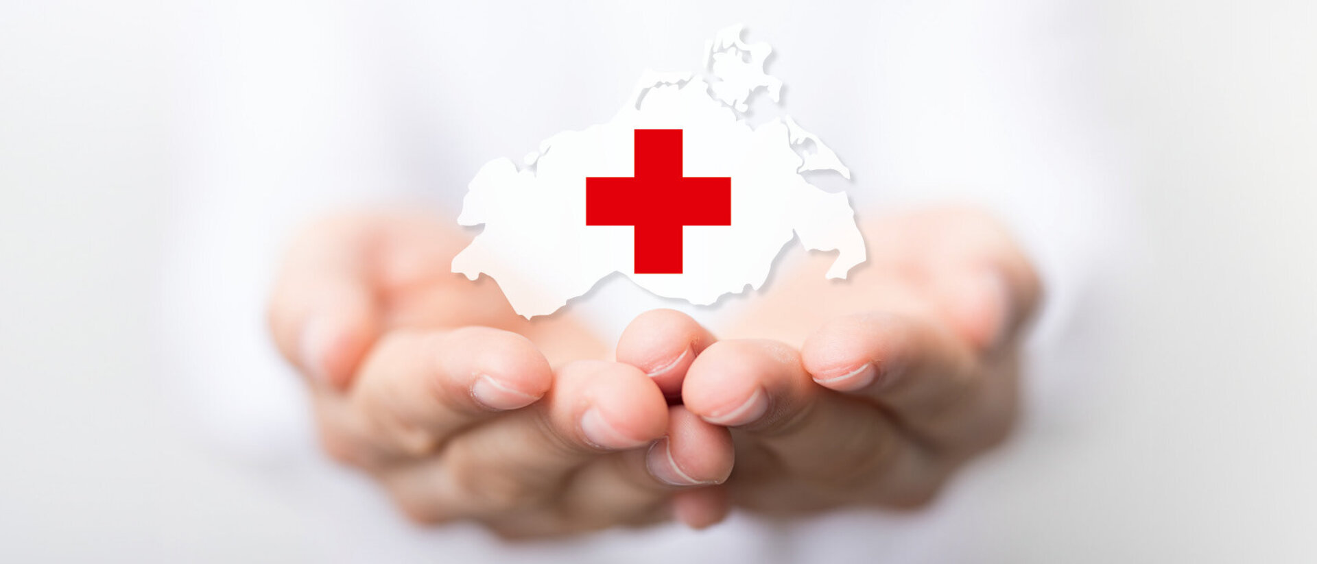 Hände halten Umriss von Deutschland mit rotem Kreuz als Symbol des Deutschen Roten Kreuzes